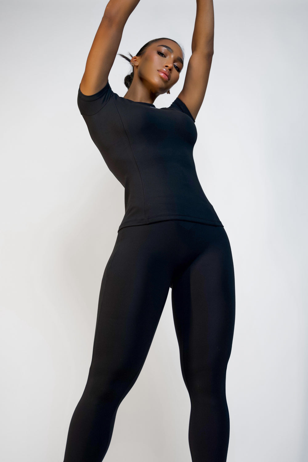 Front angle of model wearing a black short sleeve workout top with sculpting fit.