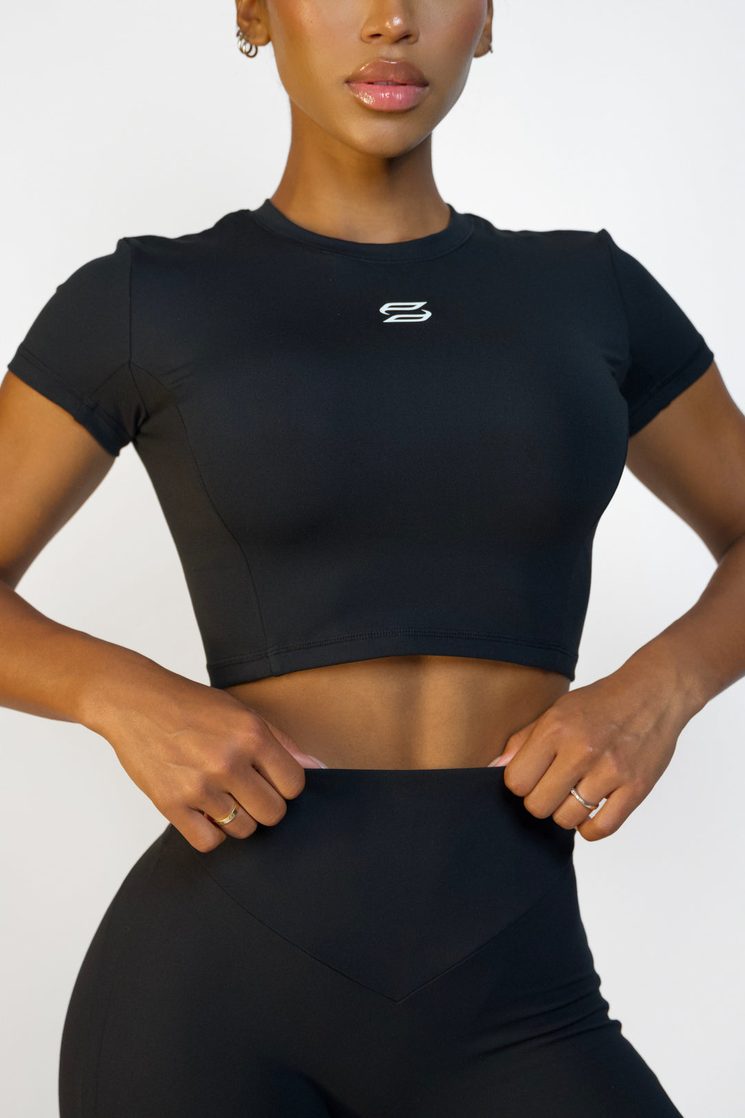 Front view of a womans black workout crop top with a high neckline
