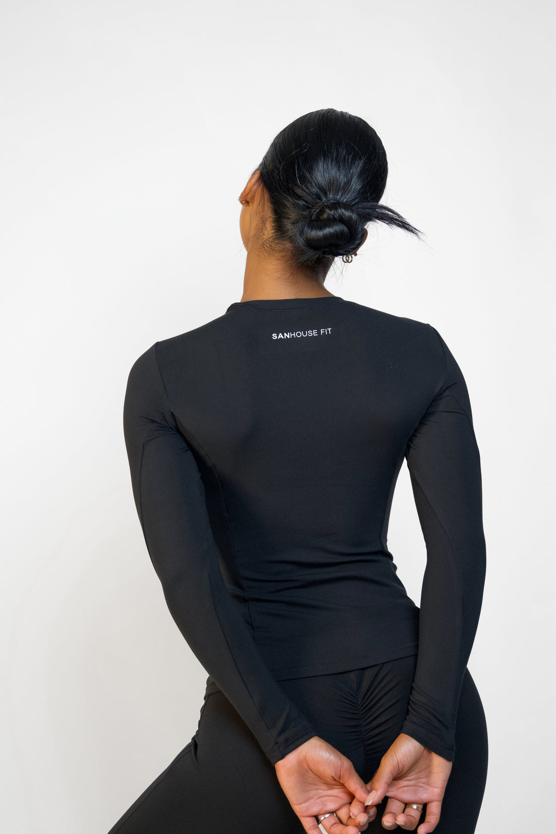 Back view of model wearing black long sleeve workout top from Sanhouse Fit